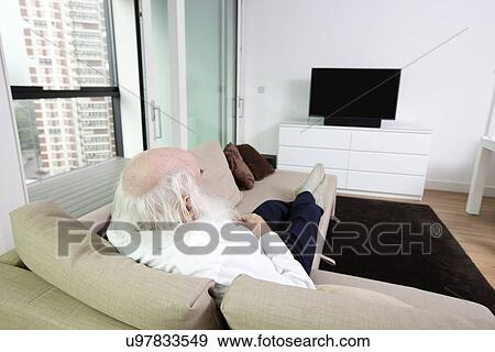 Senior man watching television in apartment View Large Photo Image Stock Photo - Senior man watching television in apartment. Fotosearch