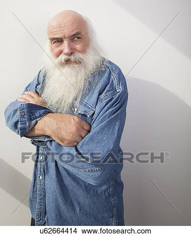 Picture - Senior man with arms crossed looking away over gray background. Fotosearch