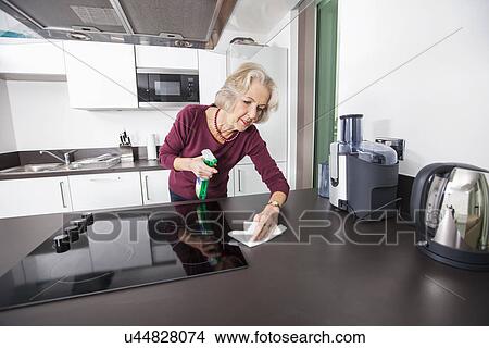 Senior woman cleaning kitchen counter View Large Photo Image Picture - Senior woman cleaning kitchen counter. Fotosearch
