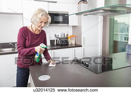 Stock Photography - Senior woman cleaning kitchen counter. Fotosearch