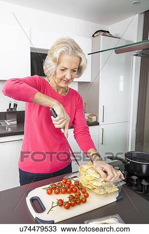 Senior woman preparing food at kitchen counter View Large Photo Image Stock Image - Senior woman preparing food at kitchen counter. Fotosearch