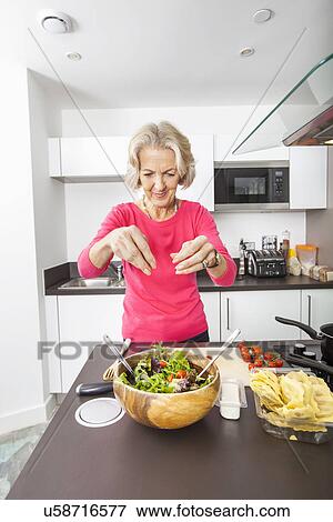 Senior woman preparing salad at kitchen counter View Large Photo Image Stock Photo - Senior woman preparing salad at kitchen counter. Fotosearch
