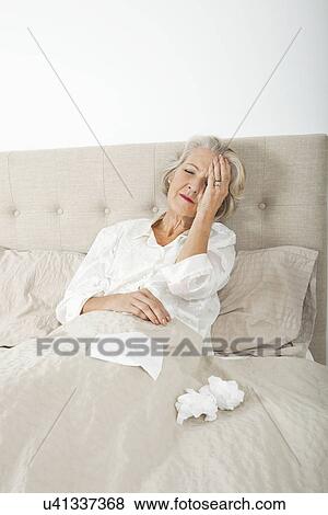 Senior woman suffering from headache resting in bed View Large Photo Image Stock Photo - Senior woman suffering from headache resting in bed. Fotosearch