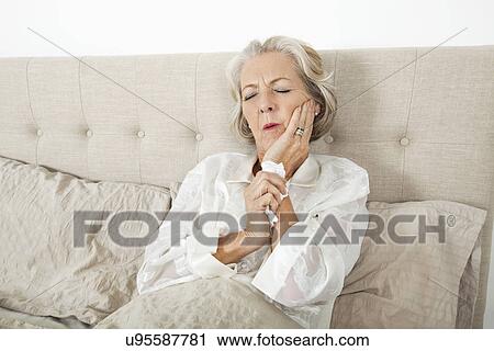 Senior woman suffering from toothache resting in bed View Large Photo Image Stock Image - Senior woman suffering from toothache resting in bed. Fotosearch