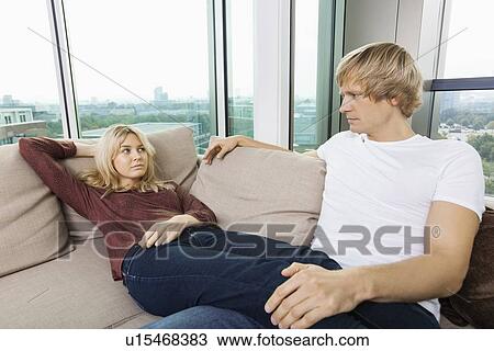 Stock Image - Serious couple looking at each other on sofa at home. Fotosearch