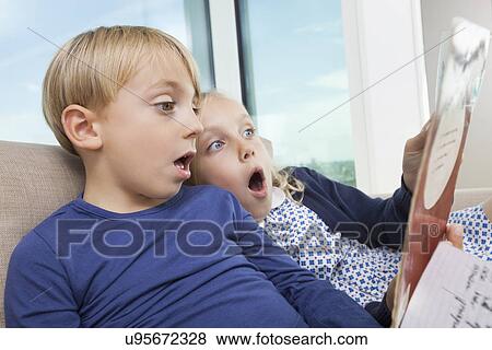 Shocked brother and sister reading storybook at home View Large Photo Image Stock Photo - Shocked brother and sister reading storybook at home. Fotosearch