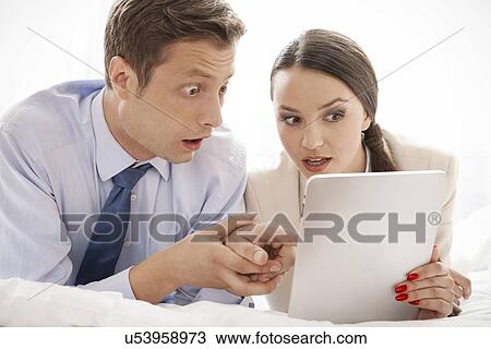 Shocked business couple using digital tablet in hotel View Large Photo Image Stock Image - Shocked business couple using digital tablet in hotel. Fotosearch