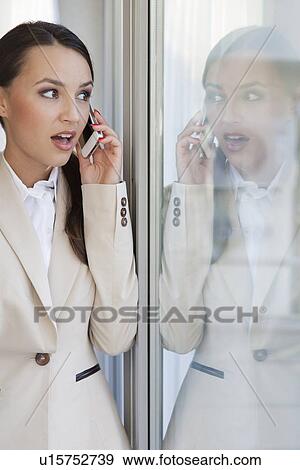 Shocked businesswoman using cell phone in office View Large Photo Image Stock Photo - Shocked businesswoman using cell phone in office. Fotosearch
