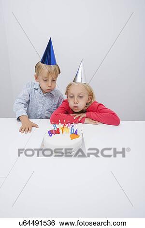 Siblings blowing birthday candles at table in house View Large Photo Image Stock Photograph - Siblings blowing birthday candles at table in house. Fotosearch