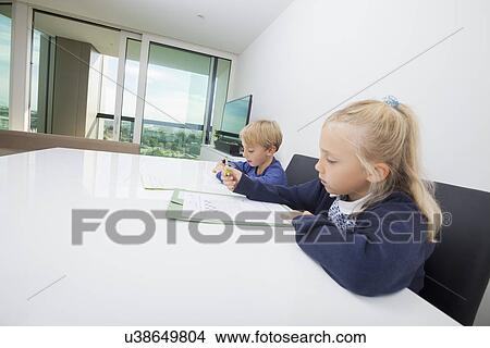 Siblings doing homework at table in house View Large Photo Image Picture - Siblings doing homework at table in house. Fotosearch