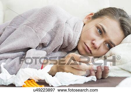 Stock Photo - Sick woman with tissue and medicines lying on bed. Fotosearch