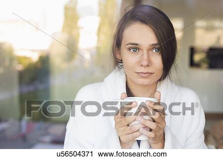 Stock Image - Sick young woman holding coffee mug at home. Fotosearch