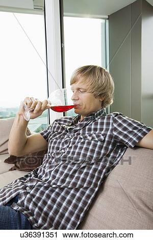 Side view of mid-adult man drinking wine in living room at home View Large Photo Image Stock Image - Side view of mid-adult man drinking wine in living room at home. Fotosearch