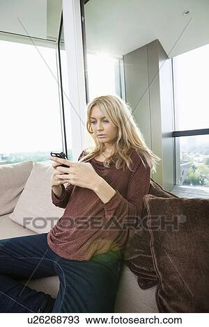Side view of young woman text messaging at home View Large Photo Image Stock Image - Side view of young woman text messaging at home. Fotosearch