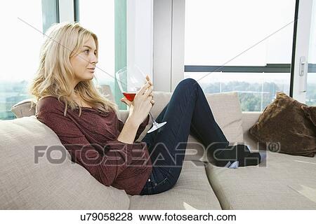 Side view of young woman with wine glass in living room at home View Large Photo Image Stock Photo - Side view of young woman with wine glass in living room at home. Fotosearch