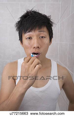 Sleepy mid adult man brushing teeth in bathroom View Large Photo Image Stock Image - Sleepy mid adult man brushing teeth in bathroom. Fotosearch