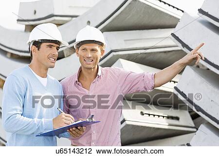 Smiling architects inspecting stock at site View Large Photo Image Stock Image - Smiling architects inspecting stock at site. Fotosearch