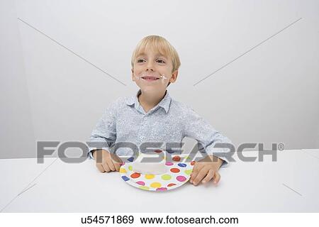 Smiling boy with cake slice in plate on table at home View Large Photo Image Stock Photo - Smiling boy with cake slice in plate on table at home. Fotosearch