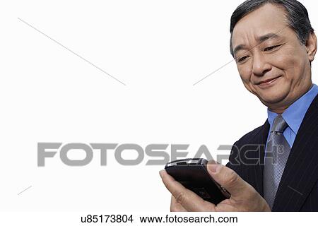 Picture - Smiling businessman using cell phone over white background. Fotosearch