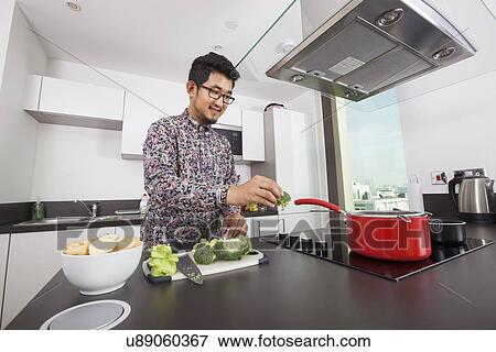 Stock Photo - Smiling man cooking in kitchen at home. Fotosearch