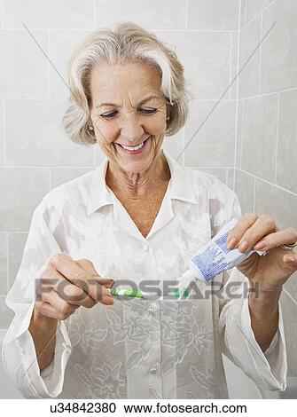 Smiling senior woman squeezing toothpaste on toothbrush in bathroom View Large Photo Image Stock Image - Smiling senior woman squeezing toothpaste on toothbrush in bathroom. Fotosearch