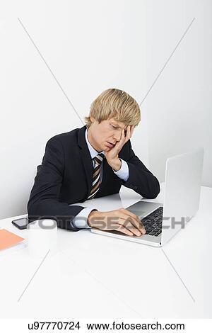 Stressed businessman using laptop at desk in office View Large Photo Image Picture - Stressed businessman using laptop at desk in office. Fotosearch