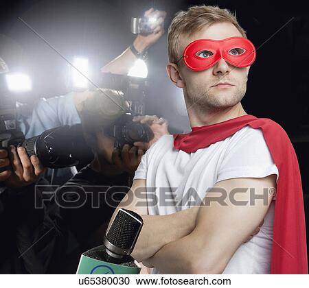 Stock Image - Superhero being photographed by paparazzi. Fotosearch