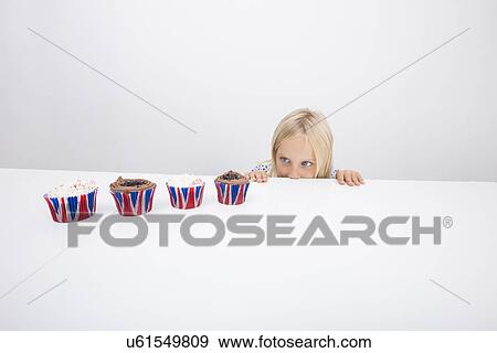 Tempted girl staring at cupcakes on table View Large Photo Image Stock Photo - Tempted girl staring at cupcakes on table. Fotosearch
