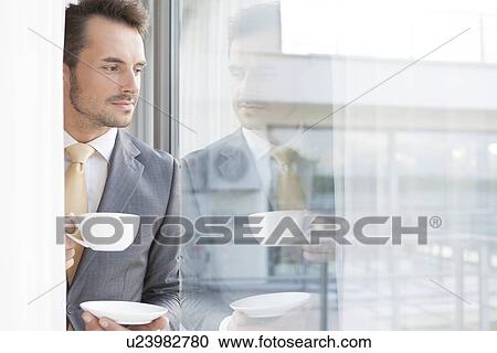 Thoughtful businessman having coffee in office View Large Photo Image Stock Image - Thoughtful businessman having coffee in office. Fotosearch