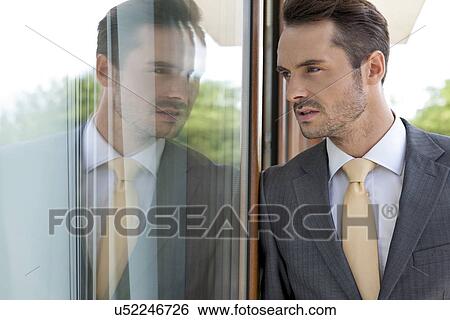 Thoughtful businessman leaning on glass door View Large Photo Image Stock Photograph - Thoughtful businessman leaning on glass door. Fotosearch