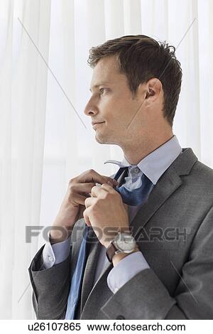 Stock Photography - Thoughtful businessman loosening necktie in hotel. Fotosearch