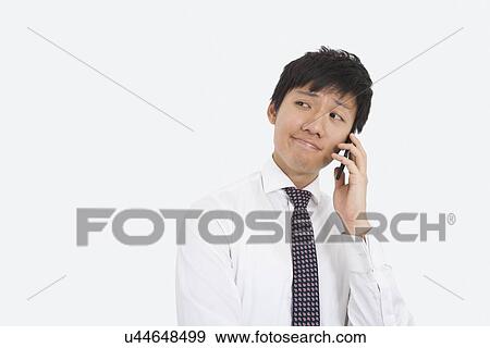 Stock Photo - Thoughtful businessman using cell phone over white background. Fotosearch