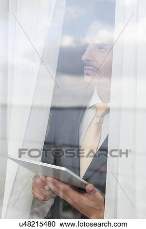 Thoughtful businessman with digital tablet in office View Large Photo Image Stock Image - Thoughtful businessman with digital tablet in office. Fotosearch
