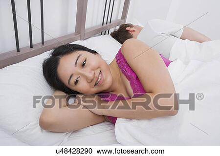 Thoughtful woman smiling while man sleeping in bed View Large Photo Image Stock Image - Thoughtful woman smiling while man sleeping in bed. Fotosearch