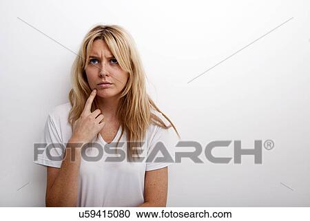 Thoughtful woman standing against white background View Large Photo Image Stock Image - Thoughtful woman standing against white background. Fotosearch