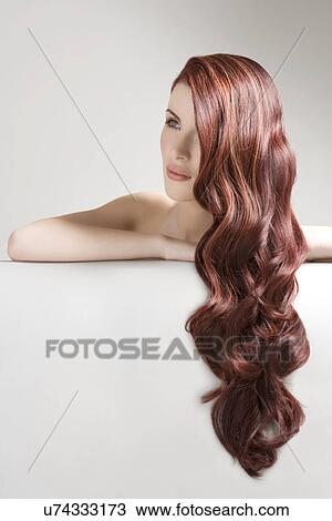 Thoughtful woman with long red dyed hair against gray background View Large Photo Image Stock Image - Thoughtful woman with long red dyed hair against gray background. Fotosearch