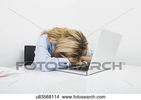 Picture - Tired businesswoman resting head on laptop at office desk. Fotosearch