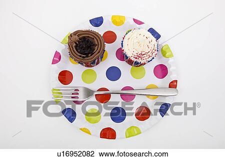 Stock Image - Top view of cupcakes in multicolored plate over white background. Fotosearch