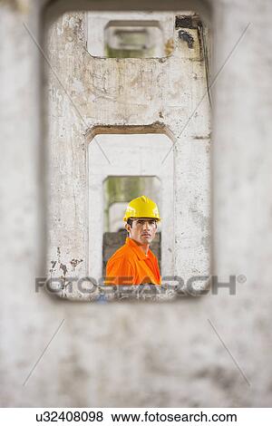 Stock Photo - View of male architect through pillars at construction site. Fotosearch