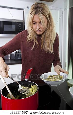 Woman serving prepared pasta in bowl at kitchen counter View Large Photo Image Stock Photo - Woman serving prepared pasta in bowl at kitchen counter. Fotosearch
