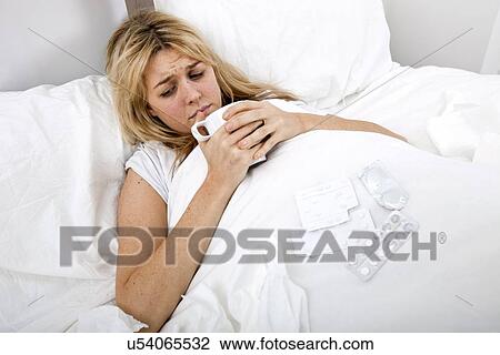 Woman suffering from cold having coffee in bed View Large Photo Image Stock Image - Woman suffering from cold having coffee in bed. Fotosearch
