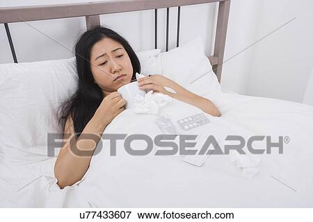Woman suffering from cold having coffee in bed View Large Photo Image Stock Photo - Woman suffering from cold having coffee in bed. Fotosearch