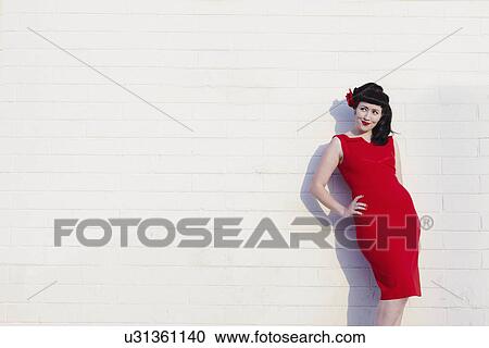 Young beautiful woman in red dress leaning on wall View Large Photo Image Stock Image - Young beautiful woman in red dress leaning on wall. Fotosearch