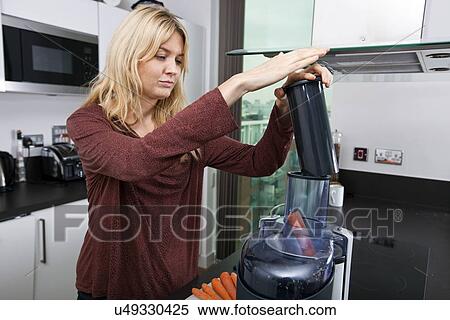 Young blond woman juicing carrots in kitchen View Large Photo Image Stock Photography - Young blond woman juicing carrots in kitchen. Fotosearch