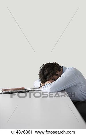 Young businessman resting head on desk View Large Photo Image Stock Image - Young businessman resting head on desk. Fotosearch