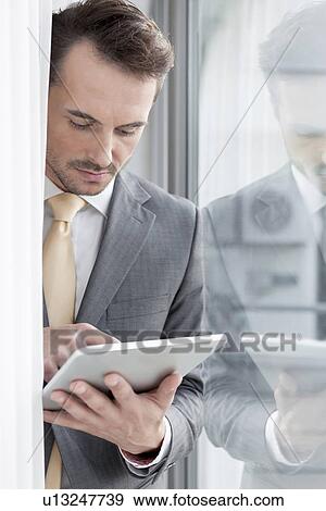 Young businessman using digital tablet in office View Large Photo Image Stock Photo - Young businessman using digital tablet in office. Fotosearch