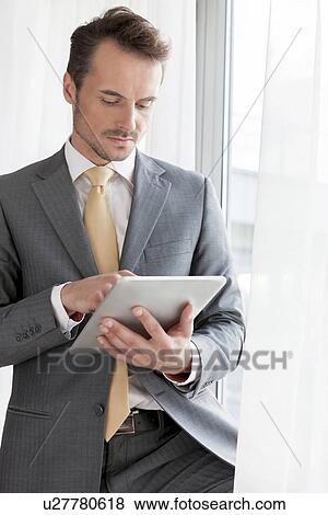 Stock Photo - Young businessman using digital tablet in office. Fotosearch
