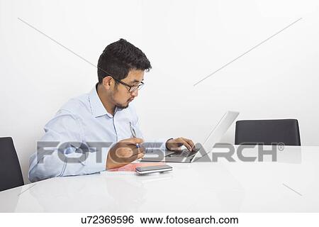 Young businessman using laptop in office View Large Photo Image Stock Photograph - Young businessman using laptop in office. Fotosearch