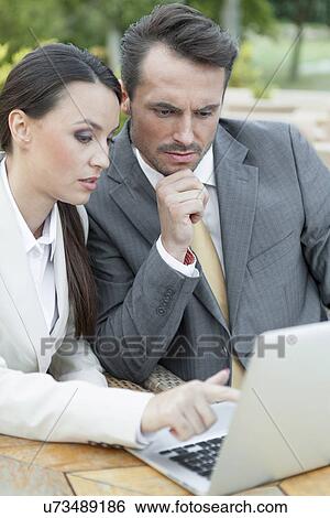 Young businesspeople discussing over laptop outdoors View Large Photo Image Stock Photograph - Young businesspeople discussing over laptop outdoors. Fotosearch