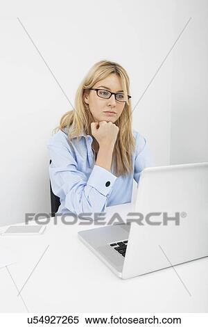 Young businesswoman looking at laptop in office View Large Photo Image Stock Photography - Young businesswoman looking at laptop in office. Fotosearch